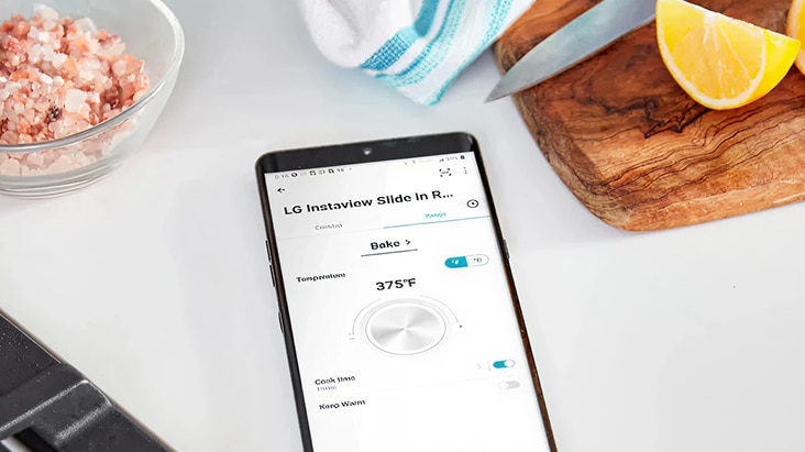 Een smartphone toont de LG ThinQ-app waarmee de LG InstaView Slide-In Range-oven wordt bediend, wat efficiënt onderhoud van het apparaat in de keuken mogelijk maakt.